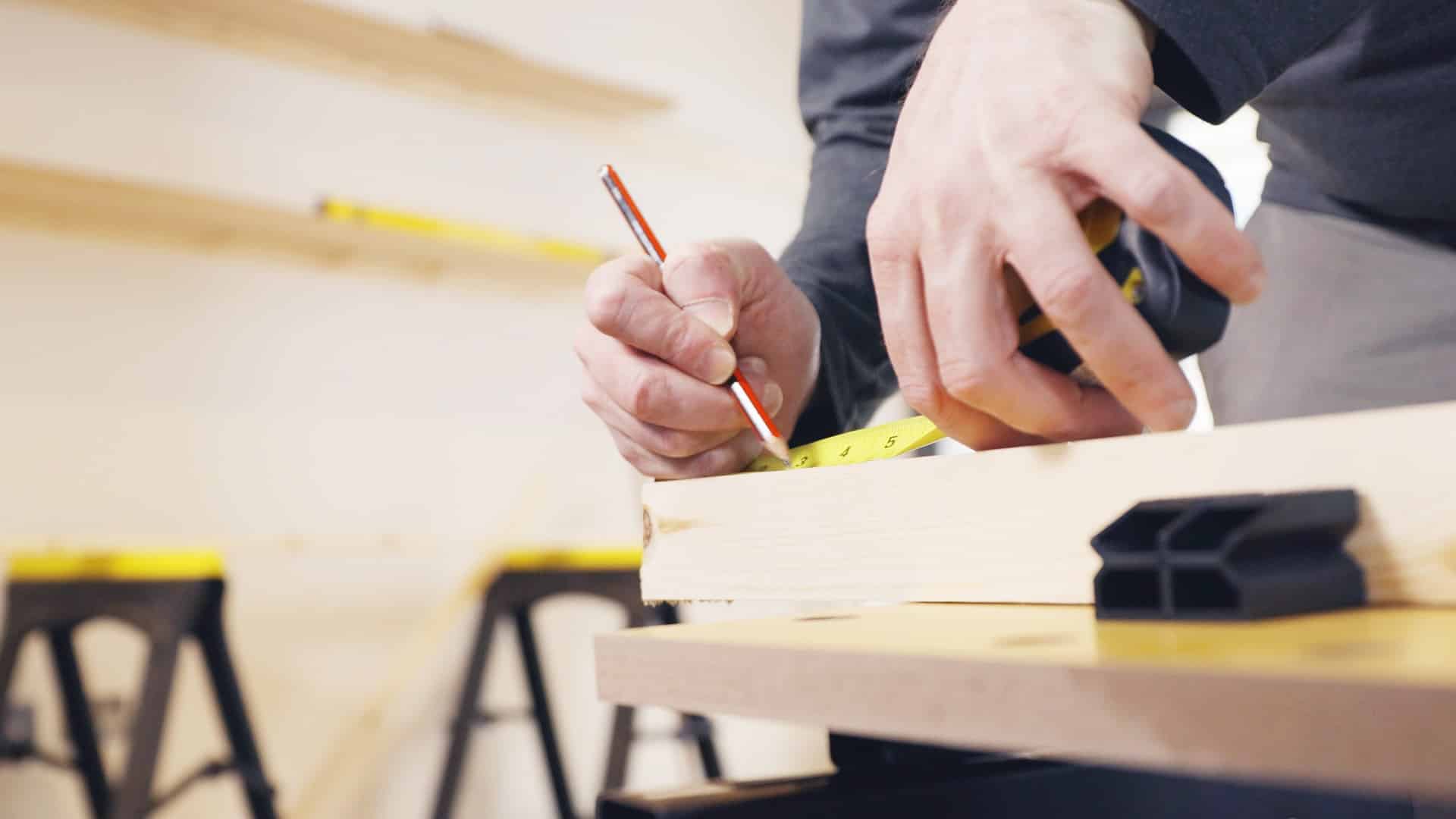 man marking wood with pencil